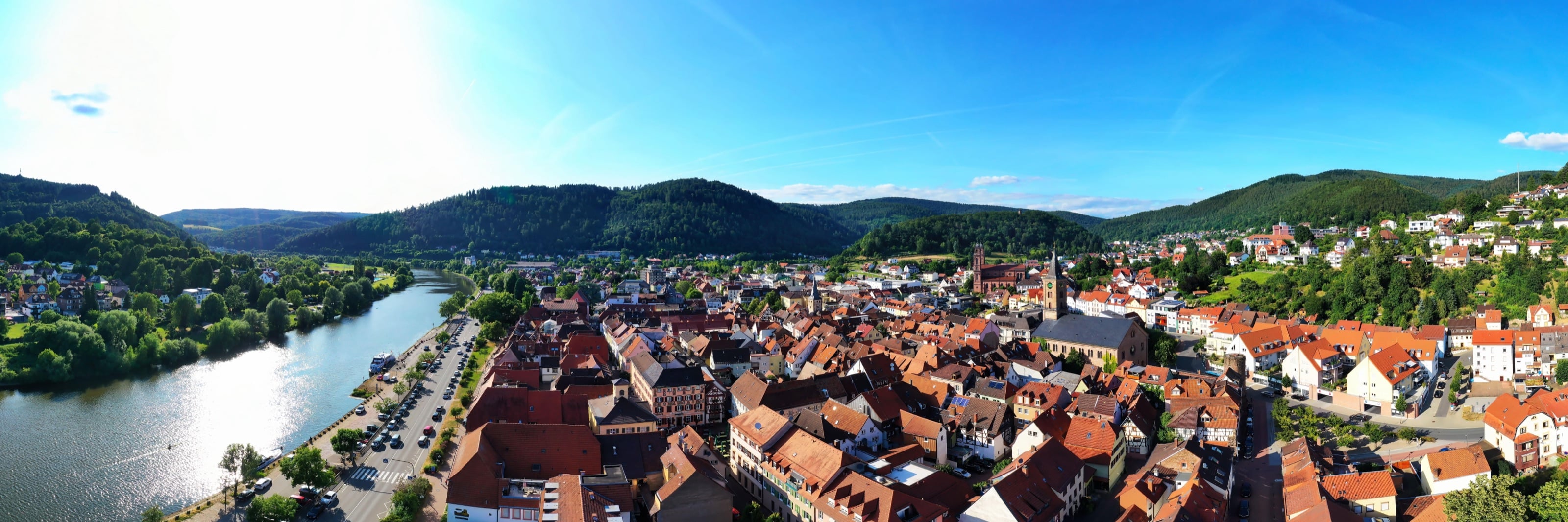 Luftaufnahme einer Altstadt im Neckartal — rote Ziegeldächer am Fluss, umgeben von bewaldeten Hügeln